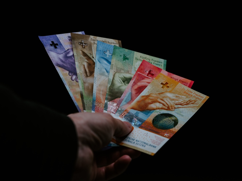 Hand mit Fächer aller aktuellen Banknoten auf schwarzem Hintergrund