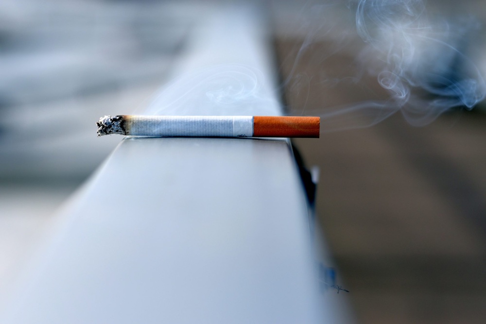 Rauchende Zigarette auf Brückengeländer